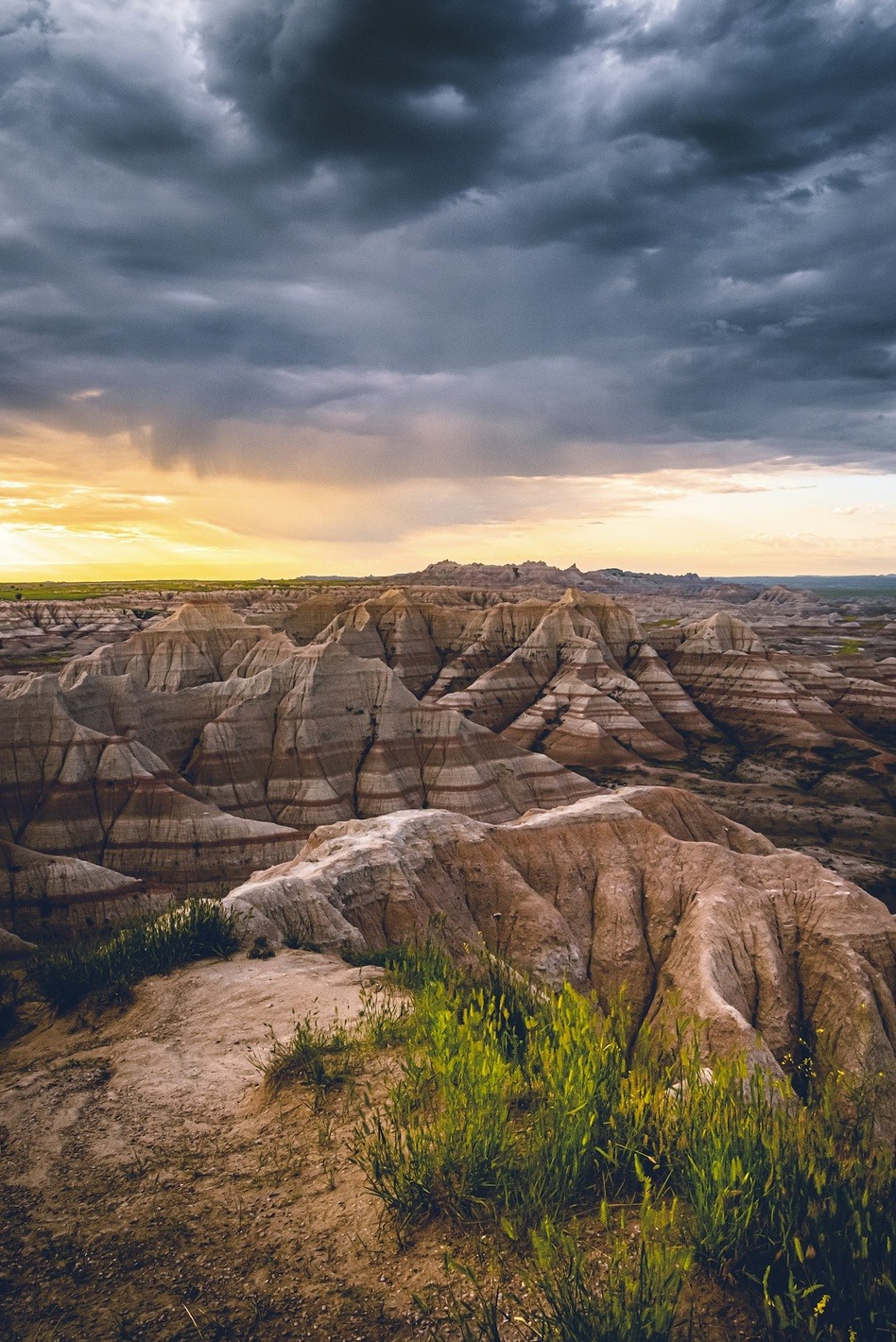 Storm clouds over striped rock formations at sunset in Badlands National Park